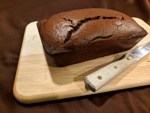 Unfrosted chocolate bread on cutting board with bread knife