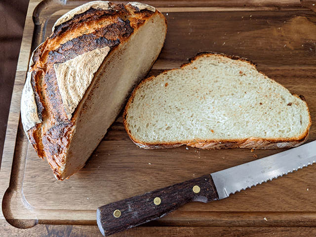 Slice of sourdough discard bread on cutting board next to bread knife