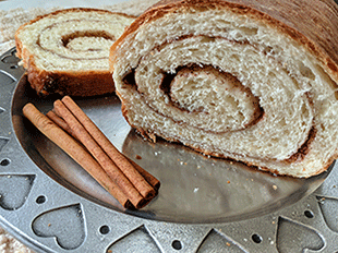 Cinnamon swirl bread on plate next to cinnamon sticks
