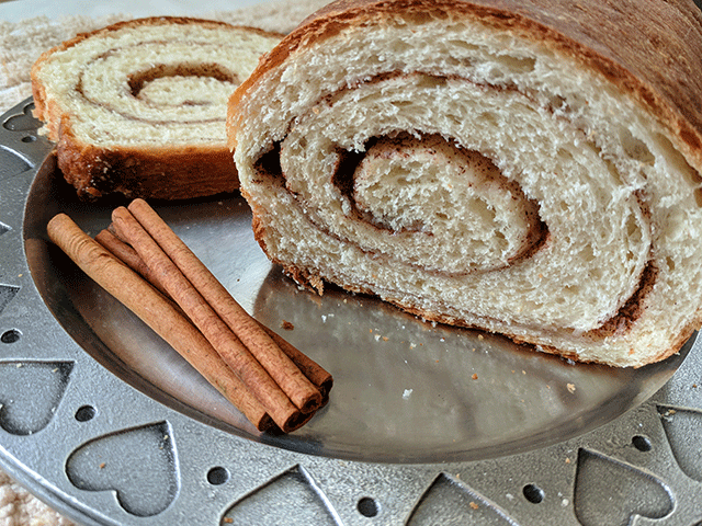 Cinnamon Swirl Bread on Plate Next to Cinnamon Sticks
