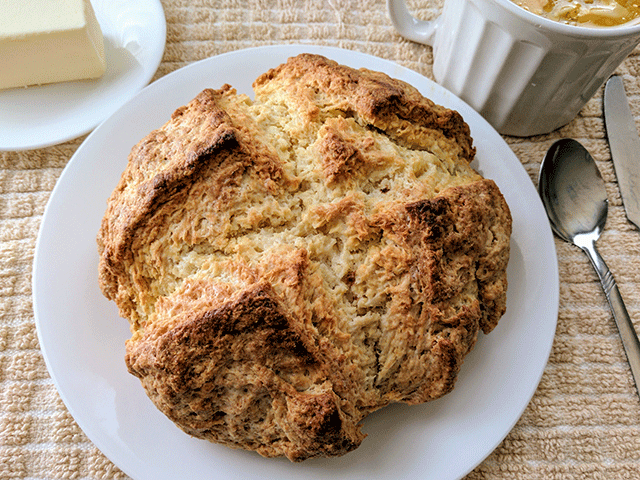 Irish Soda Bread on Plate Next to Butter and Bowl of Soup
