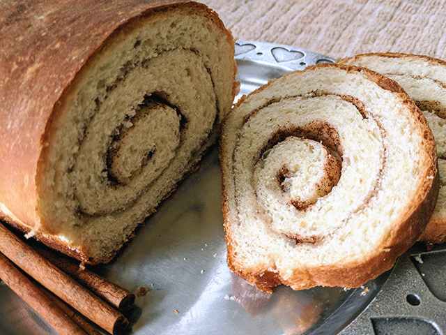 finished cinnamon swirl bread on plate next to cinnamon sticks