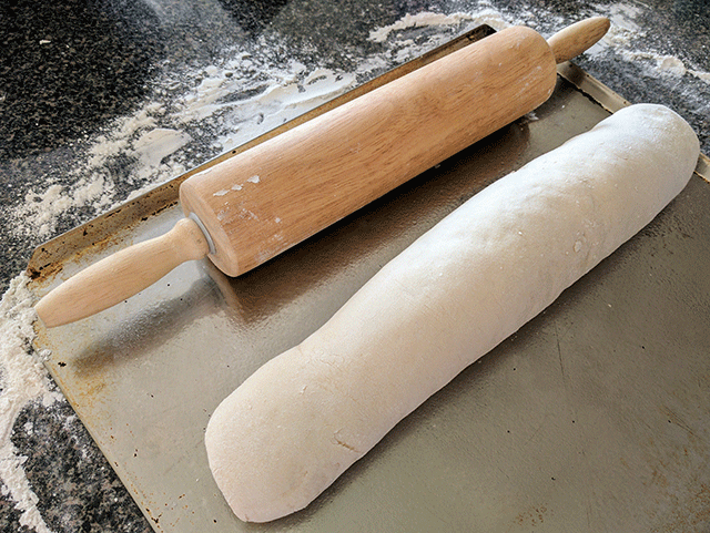 french bread dough rolled next to rolling pin