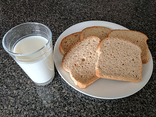 bread on a plate next to a glass of milk