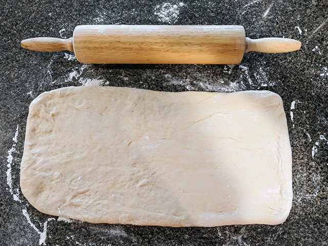 Rolled out cinnamon swirl bread dough next to rolling pin