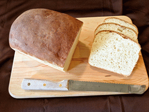 crusty sourdough cottage bread on cutting board next to bread knife