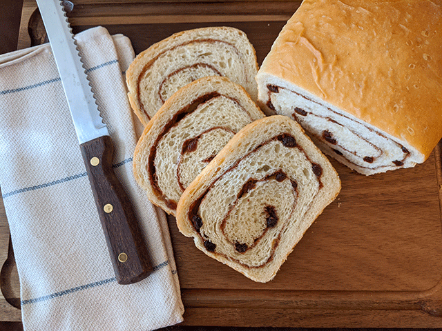 cinnamon raisin sourdough discard bread sliced on cutting board with bread knife and tea towel