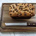 Peanut Butter Chocolate Chip Bread on Cutting Board with Knife on tea towel on wooden table