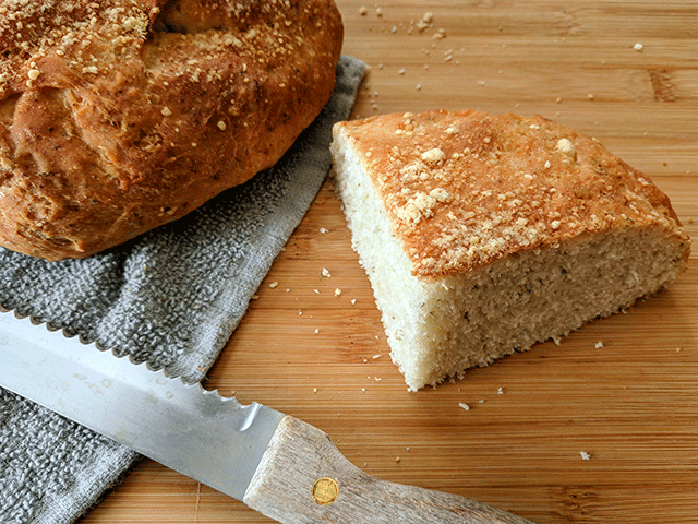 Parmesan Oregano peasant bread on cutting board with bread knife. One of several peasant bread varieties. 