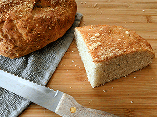 parmesan oregano peasant bread on cutting board with bread knife