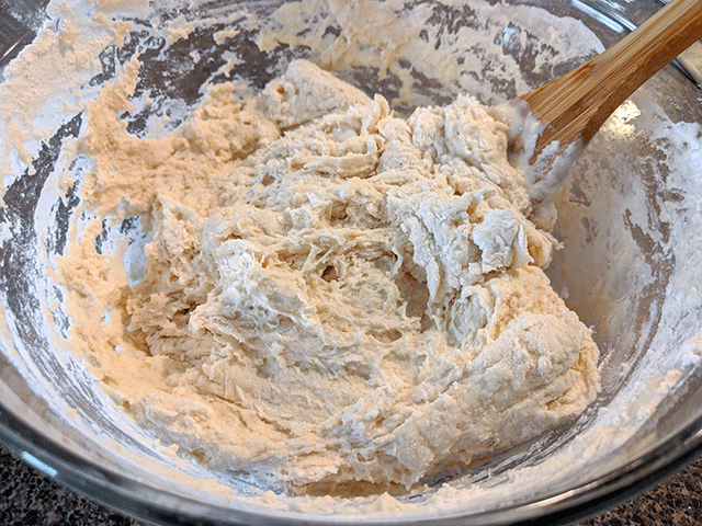 flour and water mixed in a bowl with a wooden spoon