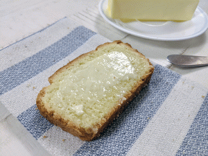 slice of buttered rice flour bread on tea towel next to butter on a plate