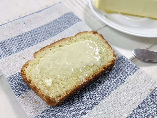slice of buttered rice flour bread on tea towel next to butter on a plate 