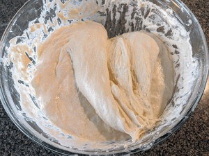 dough folded onto itself in a glass bowl