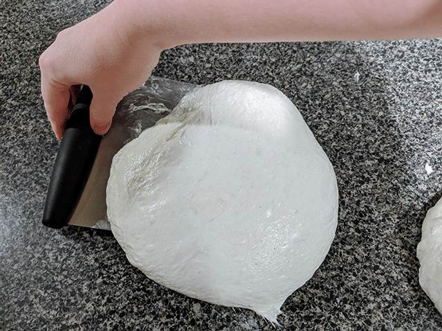 hand shapping dough round with a pastry cutter