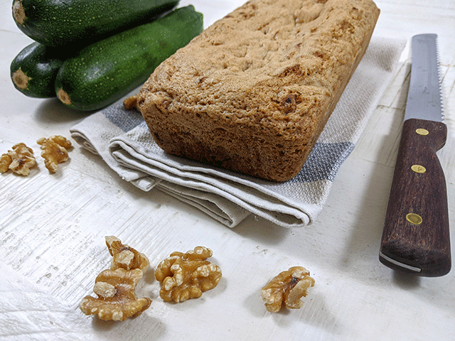 zucchini walnut bread next to zucchini and walnuts and bread knife