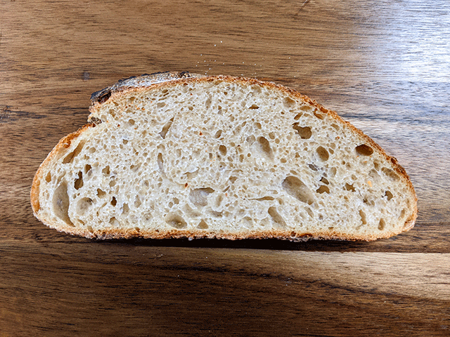 single slice of white n wheat sourdough bread on a wooden cutting board